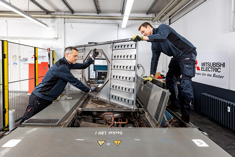 Mitsubishi Electric Service technicians working on a big metal part.